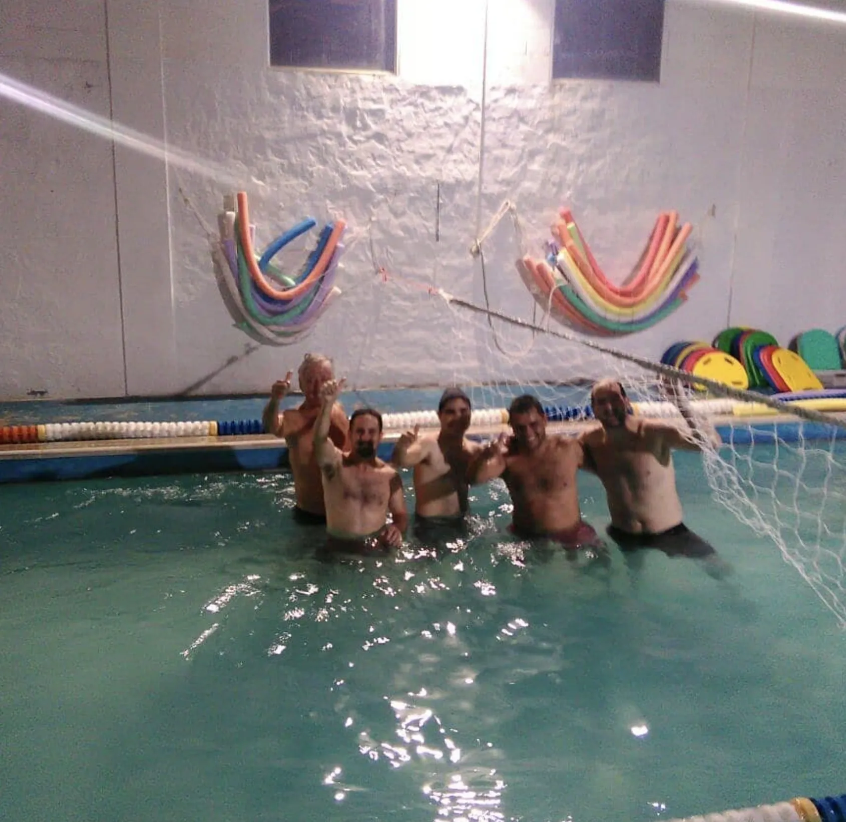 Grupo de adultos saludando desde la pileta