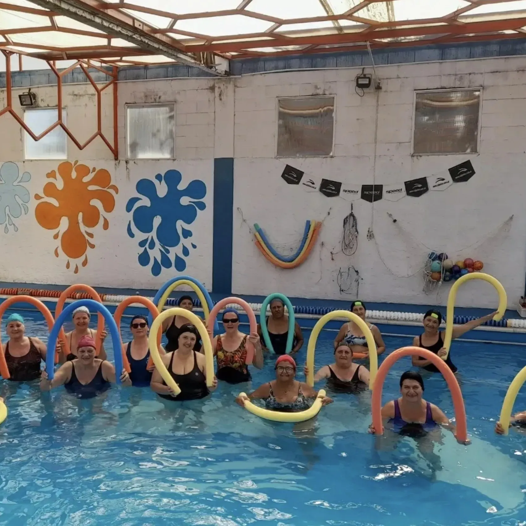 Clase de gimnasia en el agua para adultos con fideos de colores