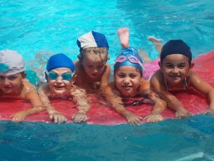 Chicos de Atlantis sonriendo sobre una colchoneta en el agua