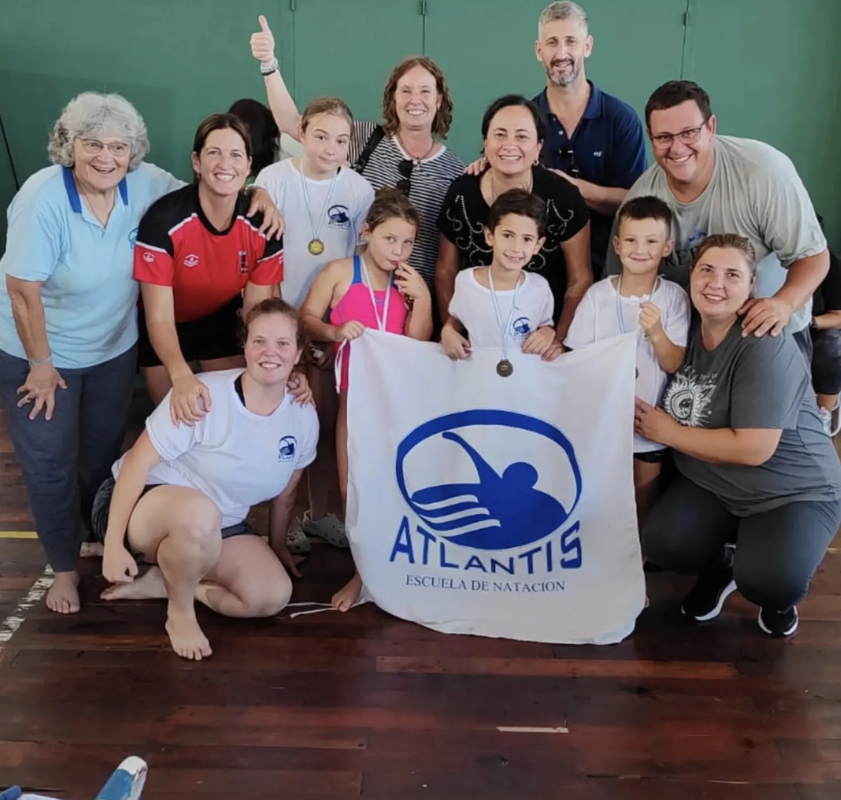 Equipo de Atlantis con familias y profes, con medallas y la bandera de la escuela
