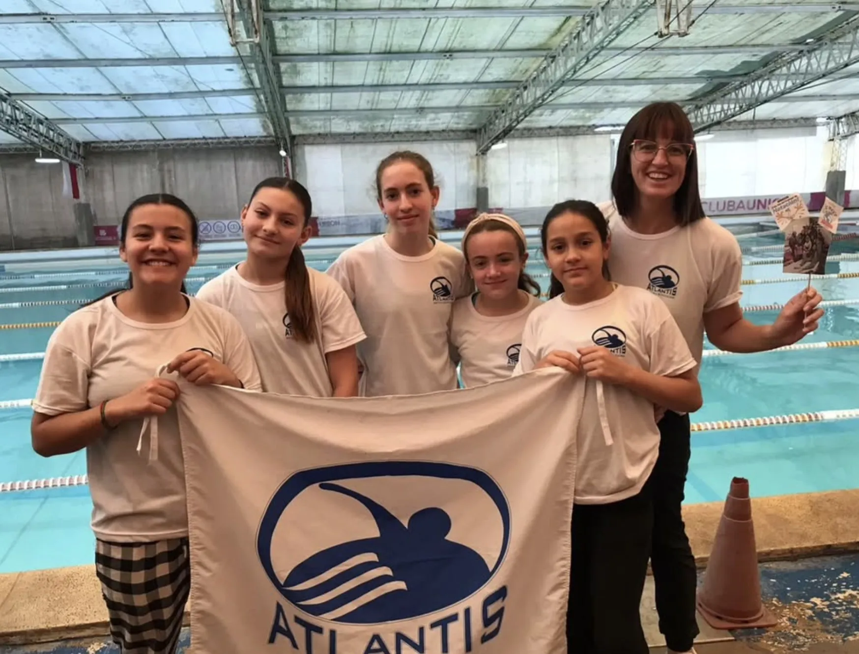 Nadadoras de Atlantis con la bandera de la escuela en un torneo