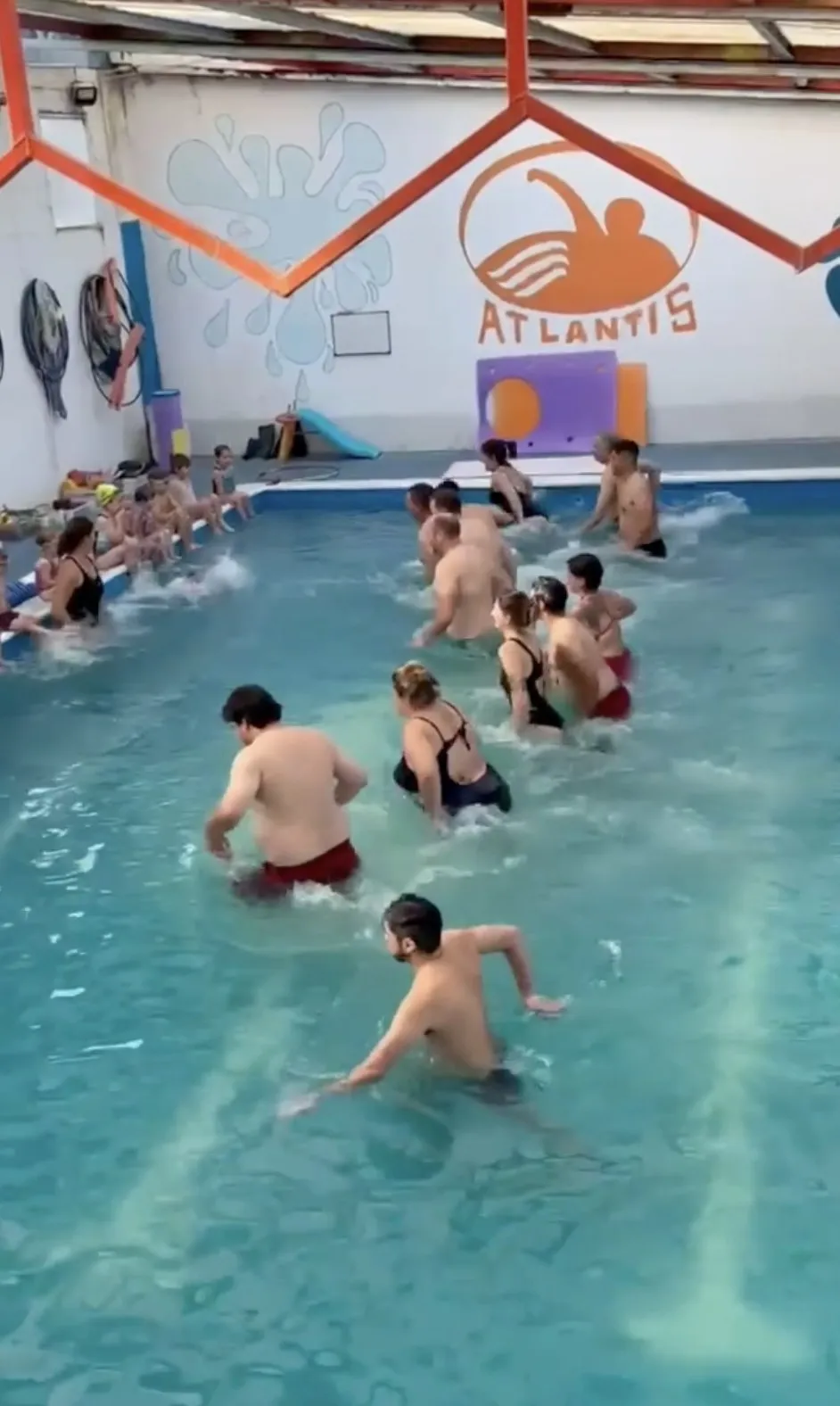 Chicos en la pileta bajo el cartel de Atlantis