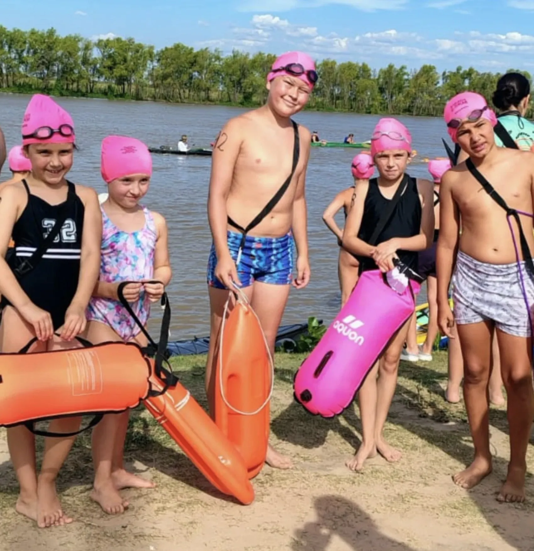 Chicos de Atlantis con gorras rosas y boyas antes de nadar en el río