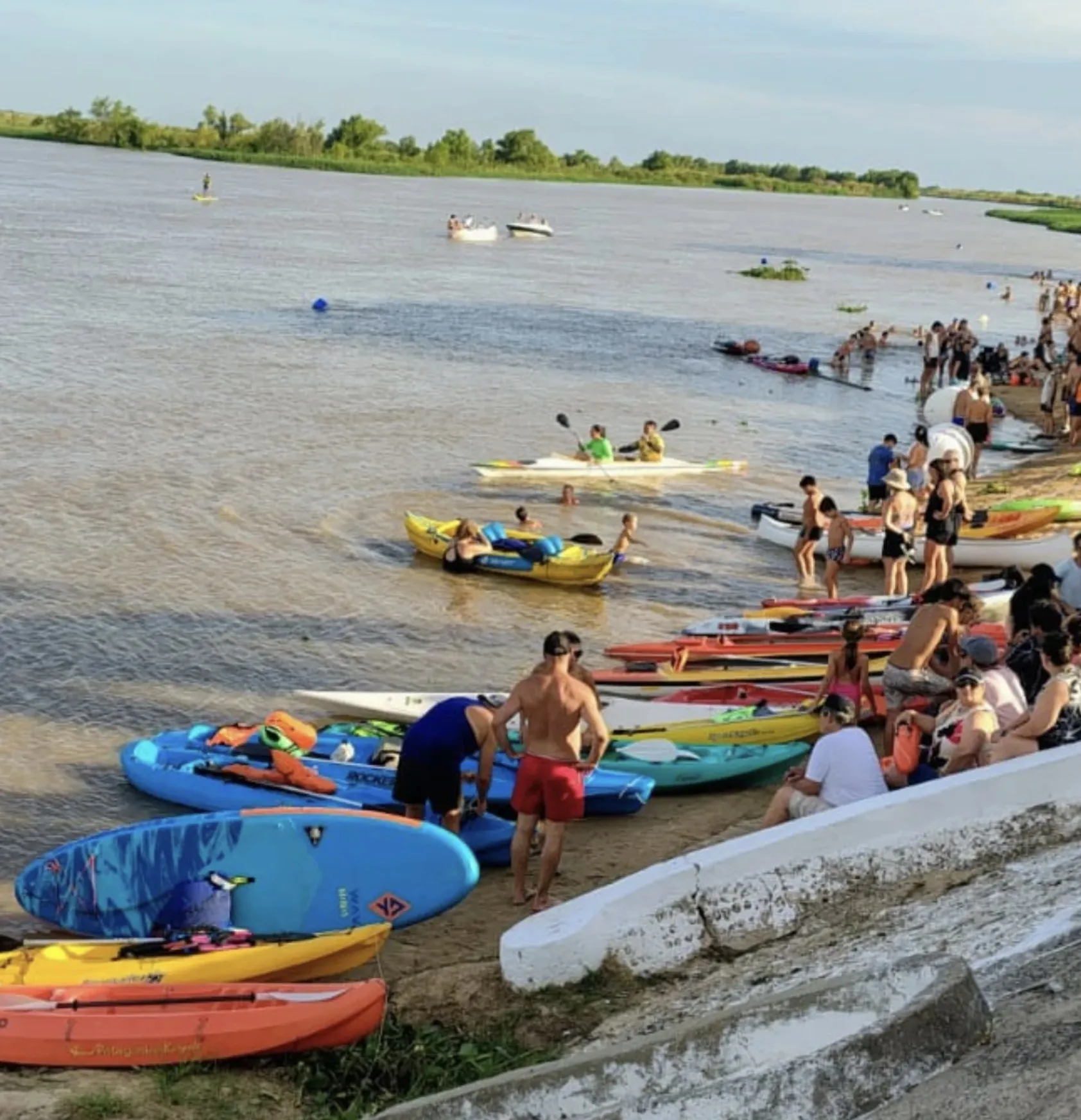 Orilla del río con kayaks y nadadores el día de la travesía