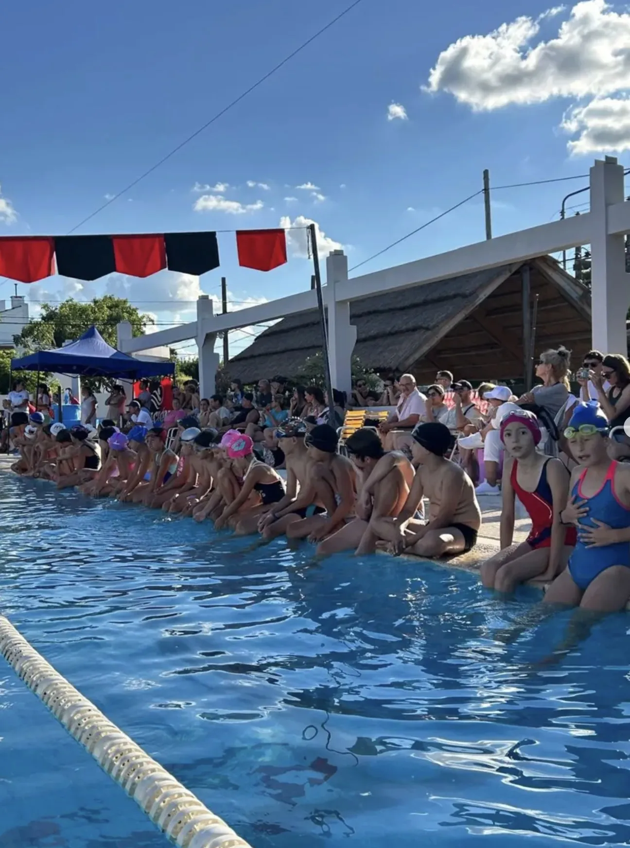 Nadadores esperando su prueba al borde de la pileta en un torneo